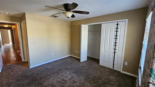 unfurnished bedroom with ceiling fan, dark carpet, and a closet