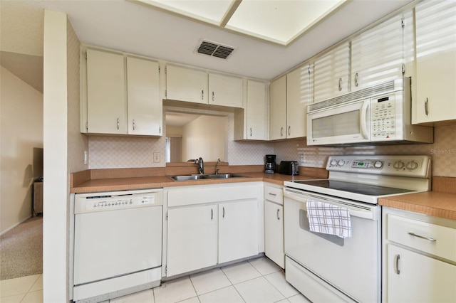 kitchen featuring tasteful backsplash, sink, light tile patterned floors, and white appliances