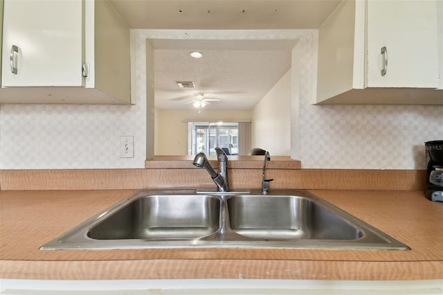 kitchen with a textured ceiling, tasteful backsplash, and sink