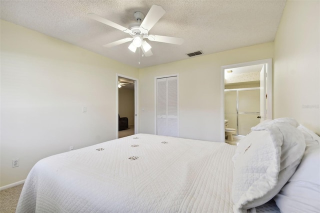 carpeted bedroom with ceiling fan, a closet, a textured ceiling, and ensuite bath