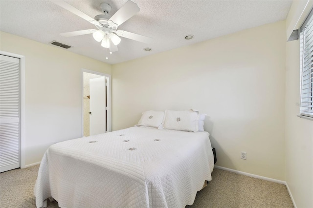 bedroom with a textured ceiling, light colored carpet, and ceiling fan