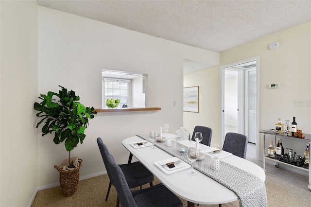 carpeted dining room featuring a textured ceiling