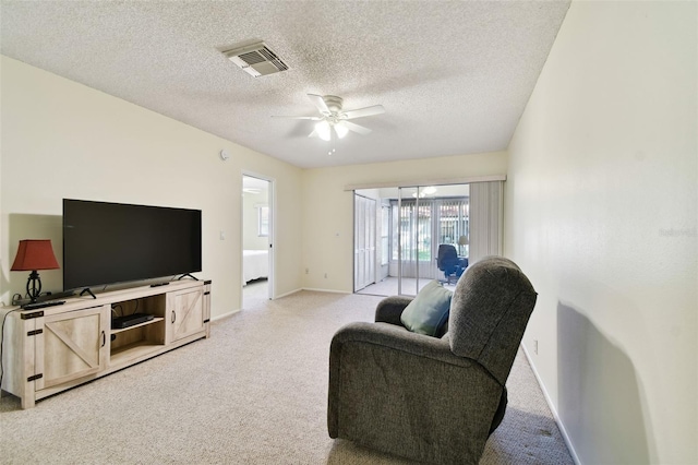 carpeted living room featuring ceiling fan and a textured ceiling