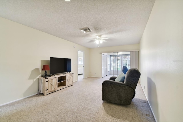 living room with ceiling fan, a textured ceiling, and light carpet