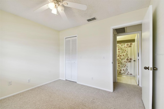 unfurnished bedroom featuring light carpet, a textured ceiling, a closet, and ceiling fan