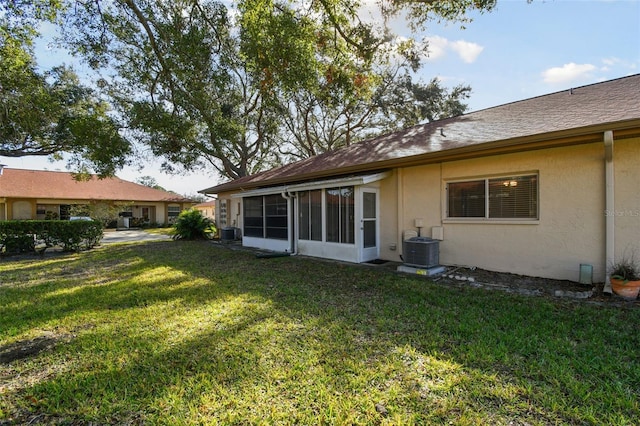 rear view of property with central air condition unit and a yard