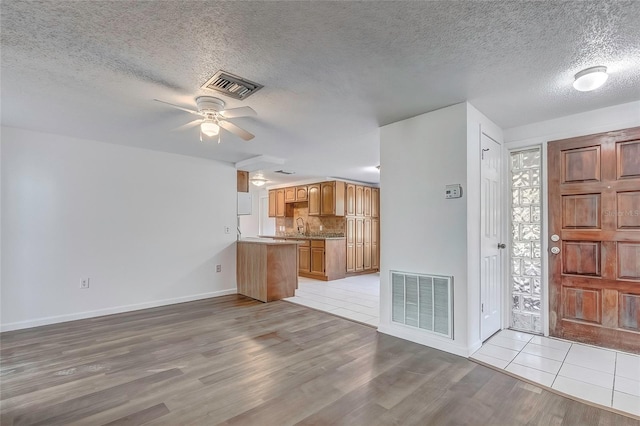 foyer with a textured ceiling, light wood-type flooring, ceiling fan, and sink