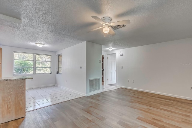 empty room featuring light wood-type flooring, a textured ceiling, and ceiling fan