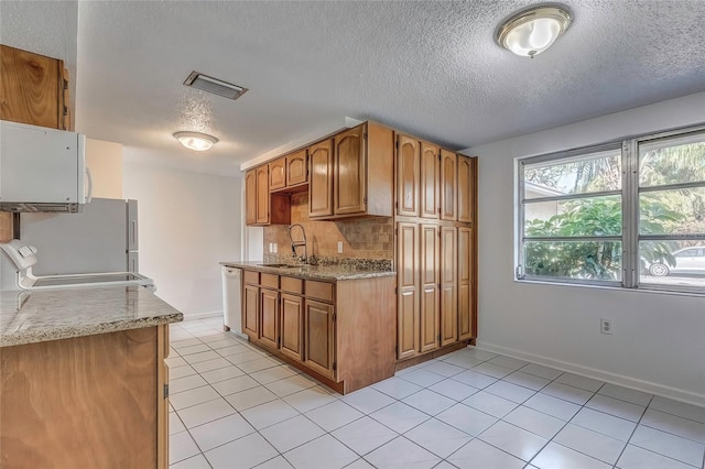 kitchen featuring a textured ceiling, sink, light tile patterned floors, and white appliances