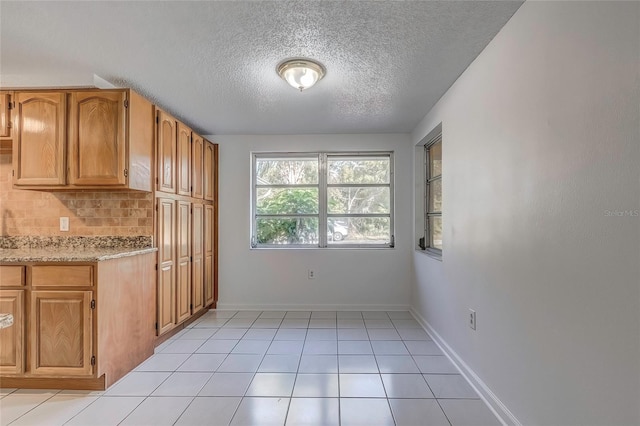 kitchen with a textured ceiling, light tile patterned floors, and backsplash