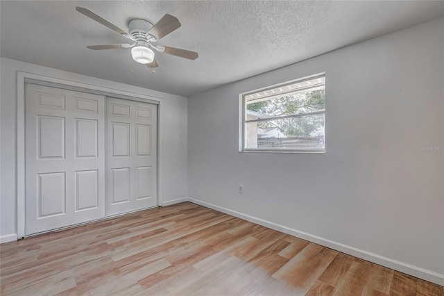 unfurnished bedroom with ceiling fan, a closet, a textured ceiling, and light wood-type flooring