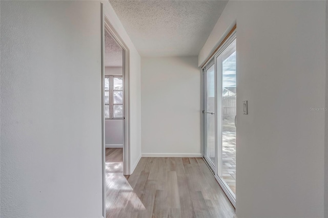 hall with a textured ceiling and light hardwood / wood-style flooring