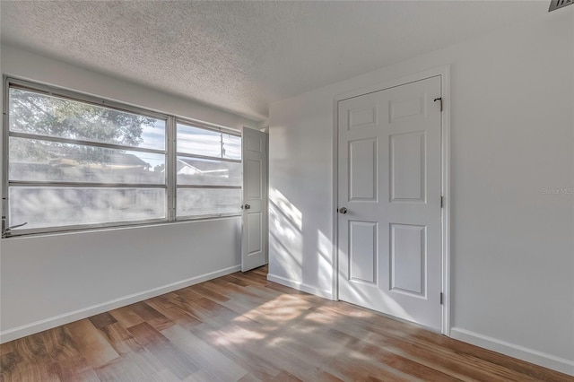 spare room featuring light hardwood / wood-style floors and a textured ceiling