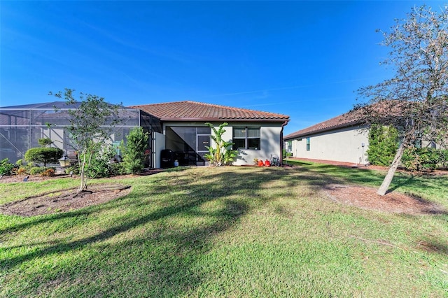 rear view of property with a yard and glass enclosure