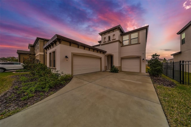 mediterranean / spanish home featuring a garage, fence, concrete driveway, and stucco siding