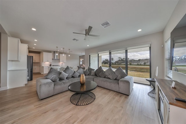 living room with light wood finished floors, visible vents, and recessed lighting