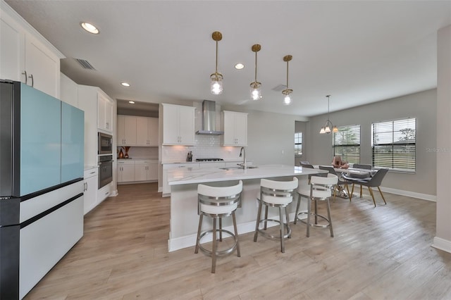 kitchen with backsplash, freestanding refrigerator, a sink, oven, and wall chimney exhaust hood