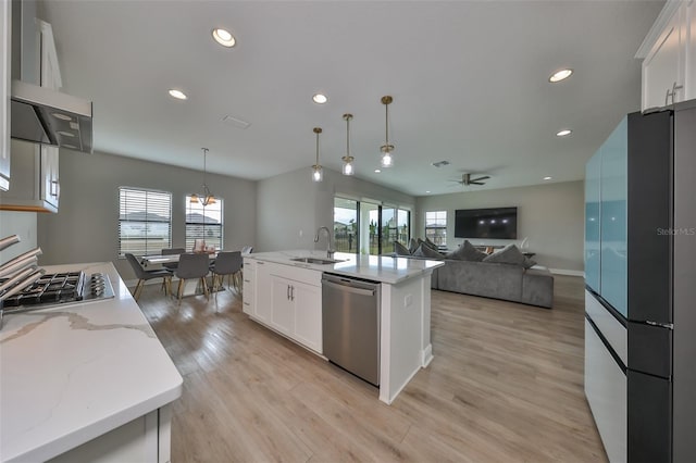 kitchen with white cabinets, appliances with stainless steel finishes, hanging light fixtures, light wood-type flooring, and a sink