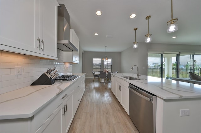 kitchen with light wood-style floors, a sink, stainless steel appliances, wall chimney range hood, and backsplash