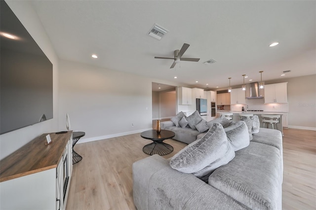 living area with baseboards, light wood finished floors, visible vents, and recessed lighting