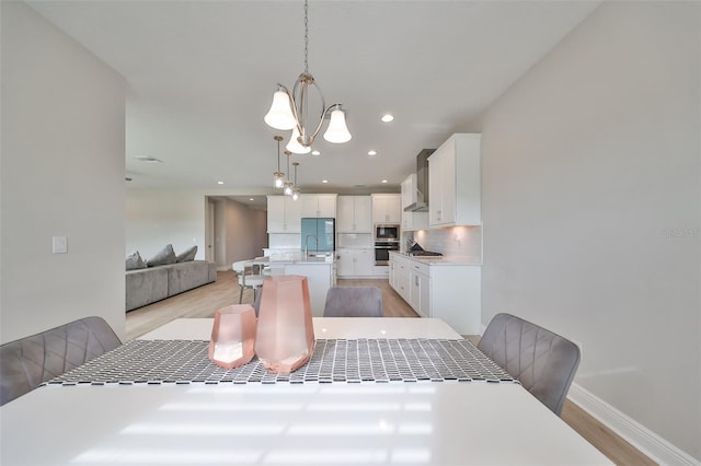 dining area with an inviting chandelier, light wood-style flooring, baseboards, and recessed lighting