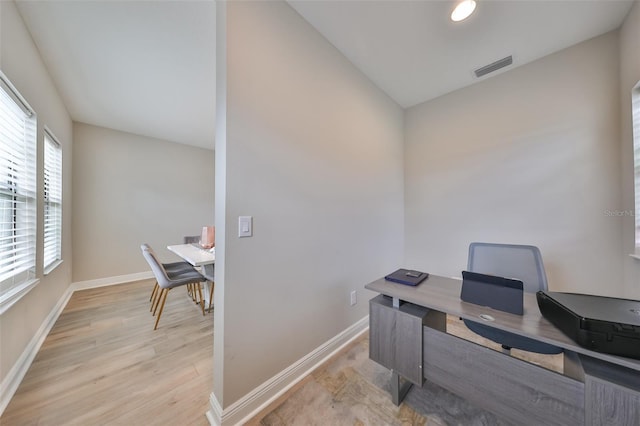 office area with light wood finished floors, baseboards, and visible vents