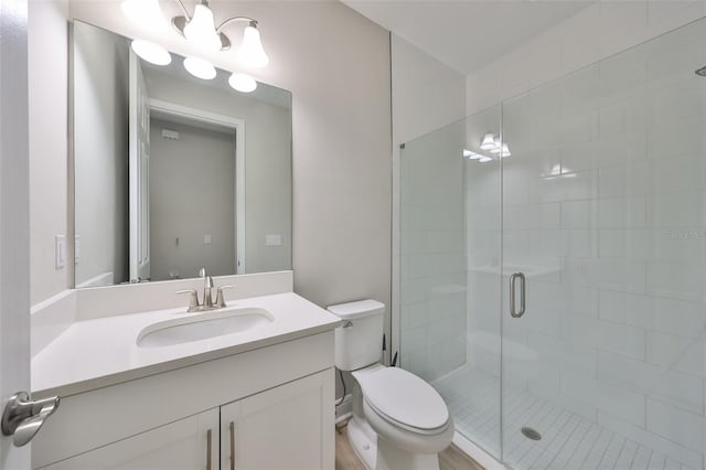 bathroom with toilet, a shower stall, and vanity