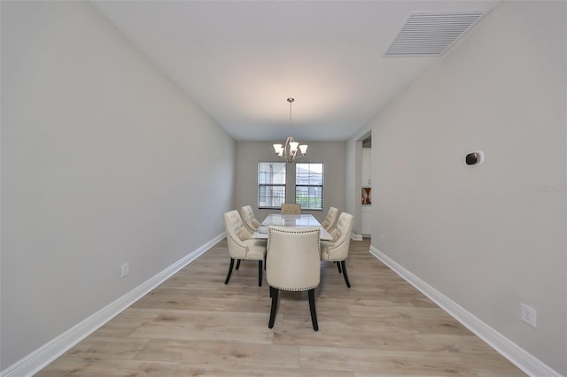 dining room with light wood finished floors, baseboards, visible vents, and a chandelier