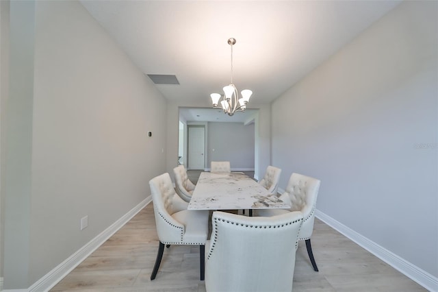 dining room featuring a chandelier, visible vents, light wood-style floors, and baseboards