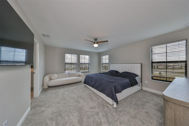 carpeted bedroom with a ceiling fan, visible vents, a textured ceiling, and baseboards