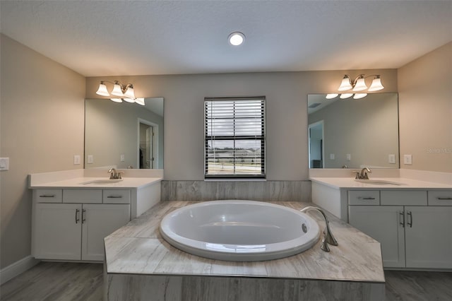 bathroom with a garden tub, two vanities, and a sink