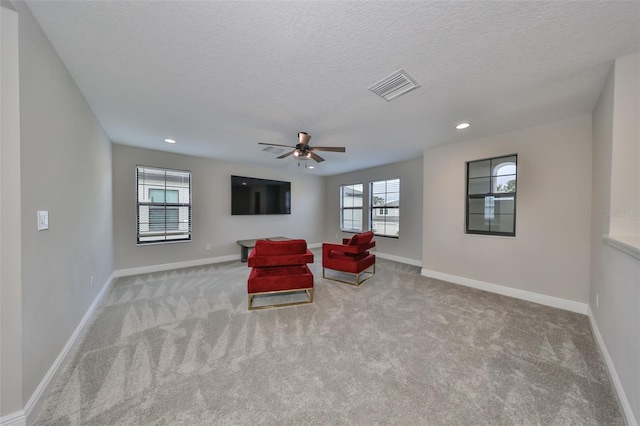 living area featuring carpet flooring, visible vents, a textured ceiling, and baseboards