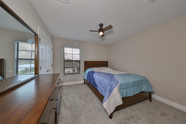 bedroom with baseboards, a textured ceiling, and light colored carpet