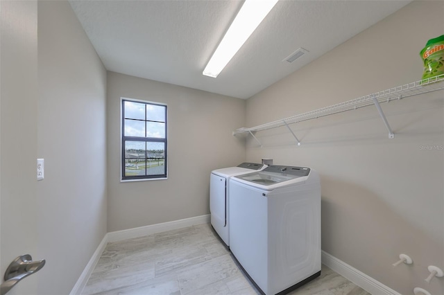 washroom with laundry area, washer and clothes dryer, visible vents, and baseboards