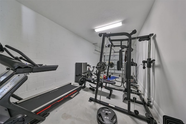 workout area with concrete block wall and a textured ceiling