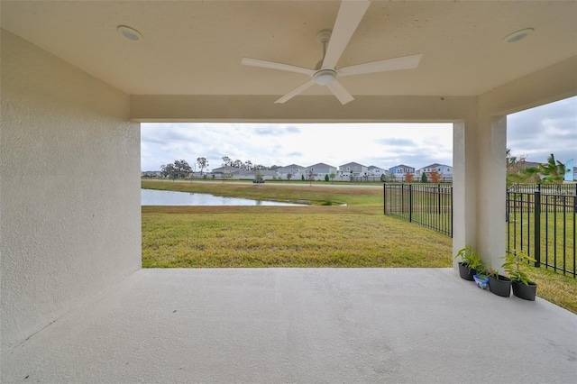 view of patio featuring a ceiling fan, a residential view, a water view, and fence