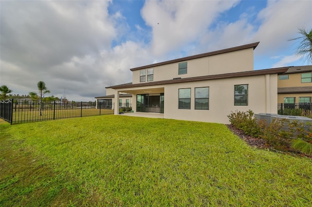 back of property featuring a yard, fence, and stucco siding