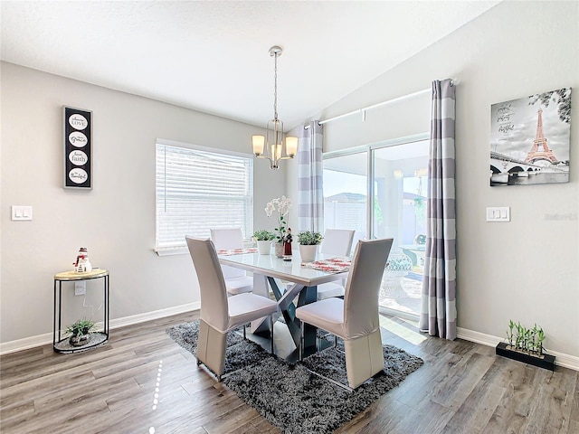 dining area featuring a chandelier, light wood-type flooring, and vaulted ceiling