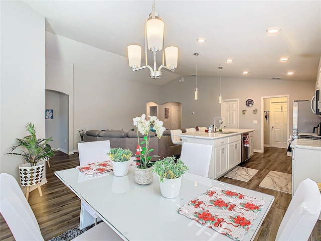 dining space with a chandelier, dark hardwood / wood-style floors, vaulted ceiling, and sink