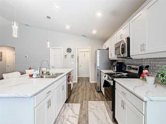 kitchen with appliances with stainless steel finishes, sink, white cabinetry, hanging light fixtures, and an island with sink