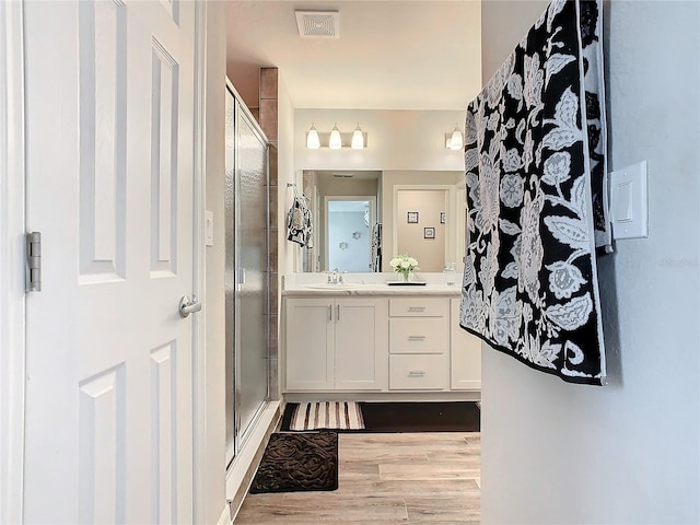 bathroom with hardwood / wood-style floors, vanity, and a shower with door