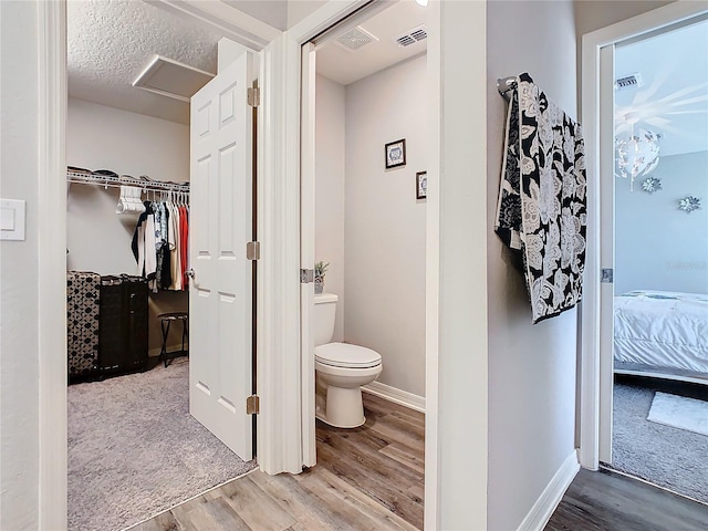 bathroom with a textured ceiling, hardwood / wood-style flooring, and toilet