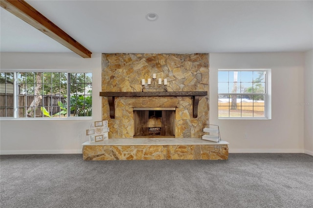 unfurnished living room featuring beam ceiling, a stone fireplace, and carpet floors