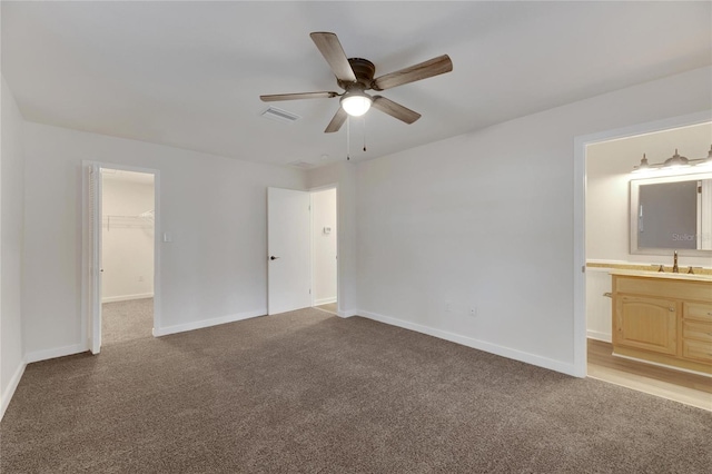 unfurnished bedroom featuring ceiling fan, a walk in closet, light carpet, and a closet