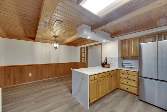 kitchen with backsplash, stainless steel fridge, light hardwood / wood-style flooring, and decorative light fixtures