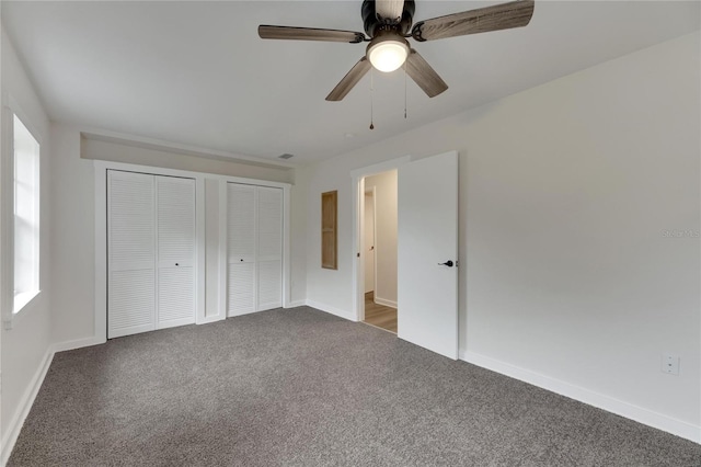 unfurnished bedroom featuring carpet floors, two closets, and ceiling fan