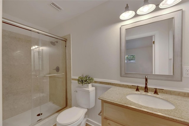 bathroom with vanity, toilet, and a shower with shower door