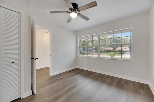 unfurnished bedroom featuring wood-type flooring, multiple windows, and ceiling fan