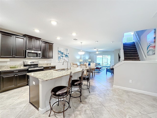 kitchen featuring sink, stainless steel appliances, a kitchen breakfast bar, pendant lighting, and a center island with sink