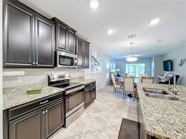 kitchen featuring light stone countertops, stainless steel appliances, ceiling fan, and sink